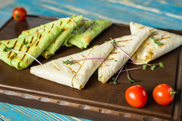 different pita bread with vegetables on a wooden board