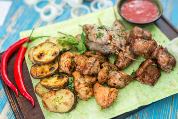 Fototapeta premium shish kebabs with vegetables and herbs on a pita bread sheet