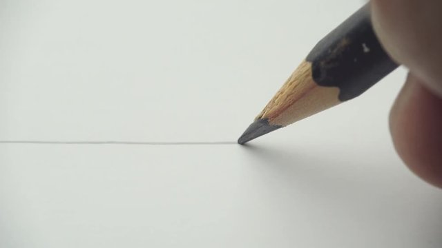 Artists hands drawing wooden pencil writes line on paper - closeup