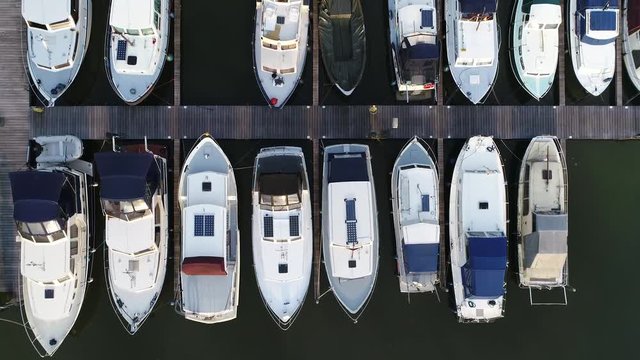 Aerial top down view of marina a dock basin with moorings and supplies for yachts and small boats showing the floating dock walkway supported by pontoons and the recreational motor boats 4k quality