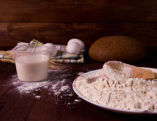 Flour, eggs, milk on a wooden background. Preparation of the dough.