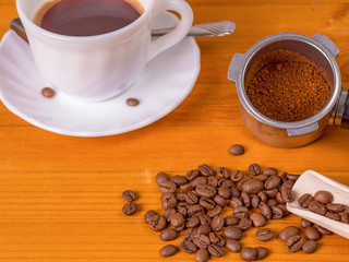 Coffee beans, dispenser and mug on a wooden background
