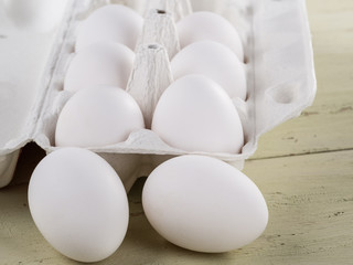 Opened packing with eggs and lying eggs next to a wooden background