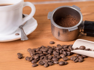 Coffee beans, dispenser and mug on a wooden background