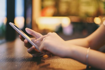 Hand of woman using smartphone on wooden table,Space for text or design.