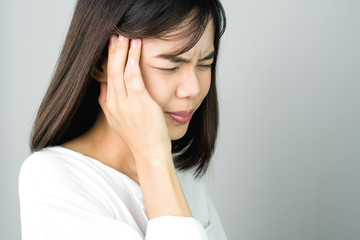 Woman in a white dress is touching head to show her headache. Causes may be caused by stress or migraine. Or because too much work. The concept of stress from hard work is bad for health.