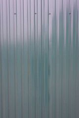 Painted and corrugated metal sheet serves as a fence, view horizontal to vertical stripes