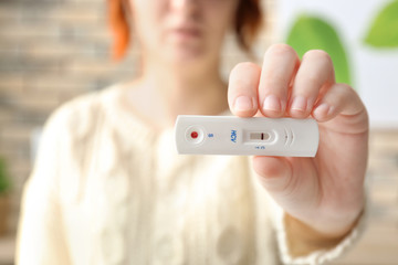 Woman holding express test for HCV on blurred background