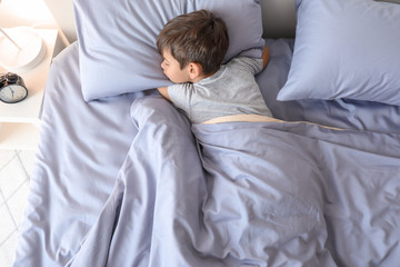 Cute little boy sleeping in bed at home