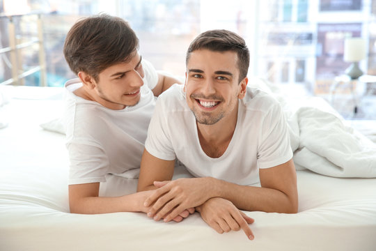 Young gay couple lying in bed at home