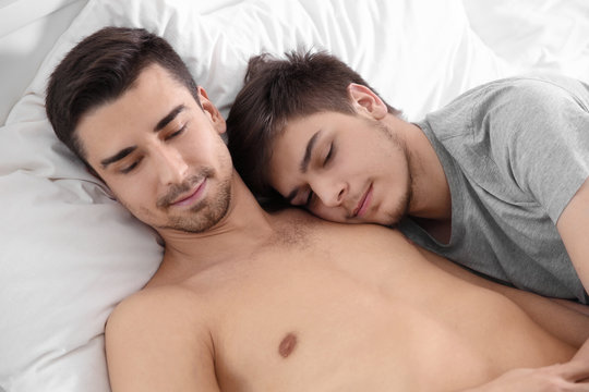 Young gay couple lying on bed at home