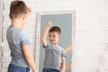 Cute little boy posing in front of mirror indoors