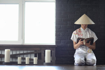 Asian boy in kimono reading an old book 