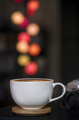 Close up white coffee cup on wooden plate and colorful blur light bokeh