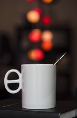 Close up white coffee cup on the book and colorful blur light bokeh in dark background