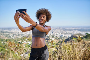 fit african american woman taking selfies at runyon canyon with los angeles in background
