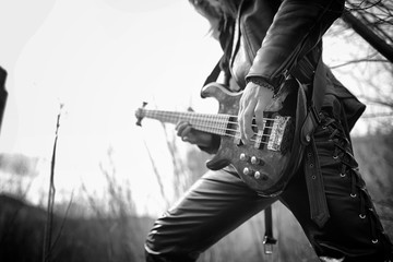 Fototapeta na wymiar Rock guitarist outdoor. A musician with a bass guitar in a leath