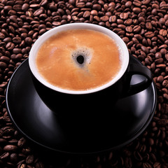 Black coffee cup filled full with espresso or americano standing on a background of dark coffee bean top view photo square format