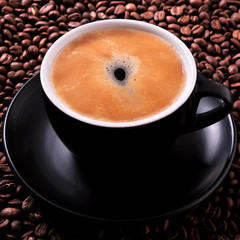 Black coffee cup filled full with espresso or americano standing on a background of dark coffee bean top view photo square format