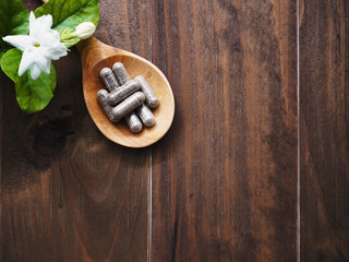 herbal pills in wooden spoon