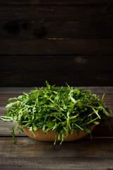 Fresh rucola with water droplets on a dark rustic background