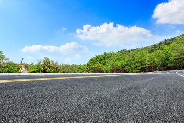 asphalt road and green forest with mountain landscape in summer