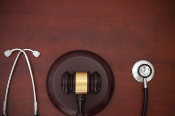 Judge gavel and stethoscope on wooden background with room for text, malpractice concept
