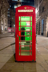 Red royal telephone booth in London city night scene