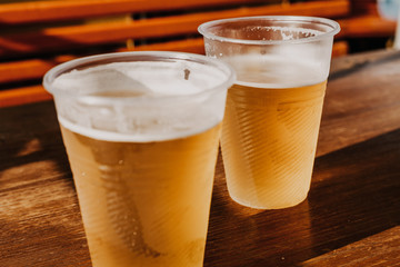 Two plastic glasses with beer stand side by side