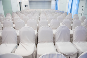Row of empty White Chairs for Business Meeting event. Interior of Conference meeting room with white chairs detail for Training Course, used as Template of The Elegant Design Office.