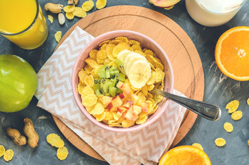 Delicious and healthy breakfast, top view. Milk, corn flakes, orange juice, orange, apple, nectarine, kiwi, banana, peanuts