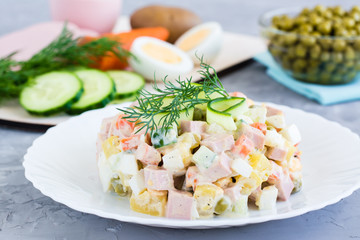 Traditional Russian salad olivier on a plate and ingredients for its preparation