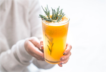 girl holding orange juice with rosemary on white background, concept of refreshing drinks