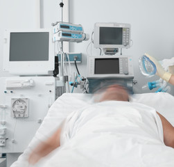 Male patient resists the nurse putting a breathing mask on him