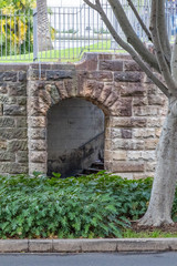 Arched sandstone entrance leading to stairs in city park
