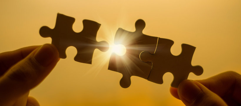 Silhouette Woman hands connecting couple puzzle piece against sunrise effect, businesswoman holding jigsaw with sunset background. Business solutions, target, success, goals and strategy concepts
