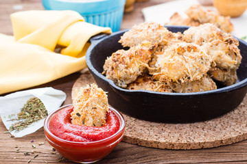 Homemade nuggets in a bowl with ketchup and a frying pan with nuggets