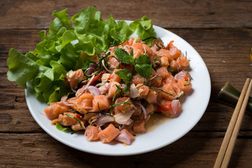 Salmon spicy salad with lemon grass  on wood background
