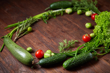 The round frame made of vegetables and herbs on a wooden background, copy space, top view