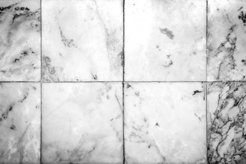Close-up of worn smooth natural marble tiles texture background with vignette in black and white