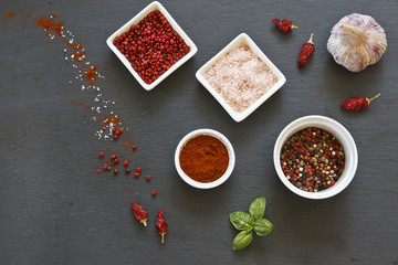 Close-up photo of colored dried spices in bowls on black concreted table background