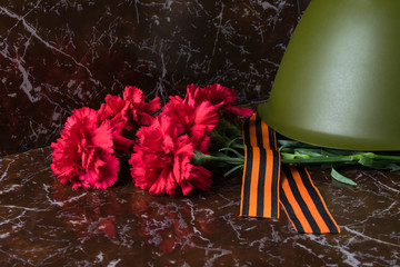 red flowers and an old military helmet on dark marble
