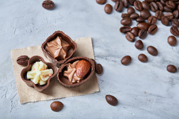 Side view of overturned glass jar with coffee beans and chocolate candies on white background,...
