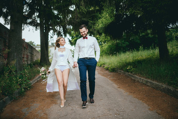 Fototapeta premium Happy newlywed couple on a walk in old European town street, gorgeous bride in white wedding dress together with handsome groom
