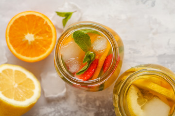 Fruit ice tea and ginger herbal ice tea with mint in a glass jars, white background, top view, copy space. Summer refreshing drink concept.