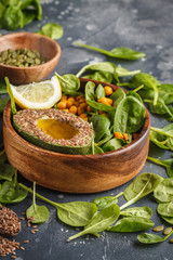 Healthy vegetarian salad with tofu, chickpea, avocado and sunflower seeds. Healthy vegan food concept. Dark background, copy space.