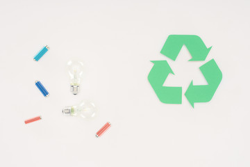 top view of light bulbs and batteries with recycle sign on white