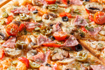 Italian kitchen and cooking concept. Hot tasty sliced with ham, sausage, jalapenos, mushrooms, tomato. Eat delivery concept.