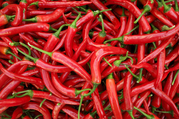 Colorful pile of red ripe organic hot chili cayenne italian frying peppers texture background(red, orange and green). Clean eating concept. Spicy vegan diet food for spring detox. Close up top view.