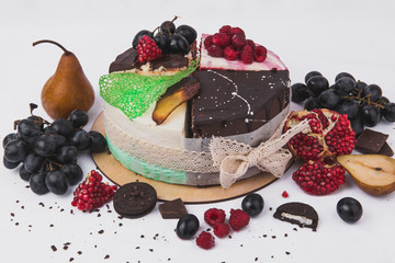 Cakes decorated with raspberries, pears, biscuits, grapes, pomegranates on a white background